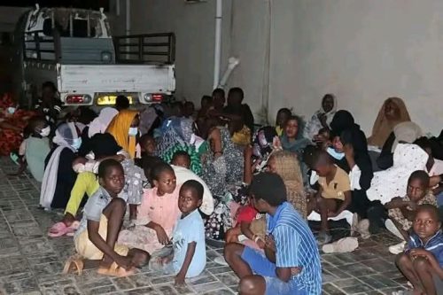 الصورة تظهر أعداد من الأطفال الونساء والرجال اللاجئين في ليبيا في دهليز جماعي يلتحفون الأرض 